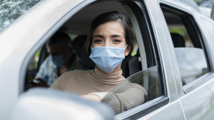 Ilustrasi mudik Beautiful Latin woman from Bogota Colombia between 20 and 29 years old, looks at the camera in a portrait and checks her cell phone waiting for a service to offer while wearing her mask