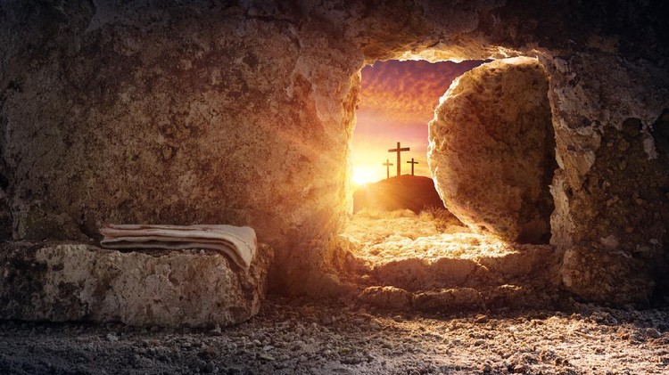 Empty tomb of Jesus at sunrise with crosses in background