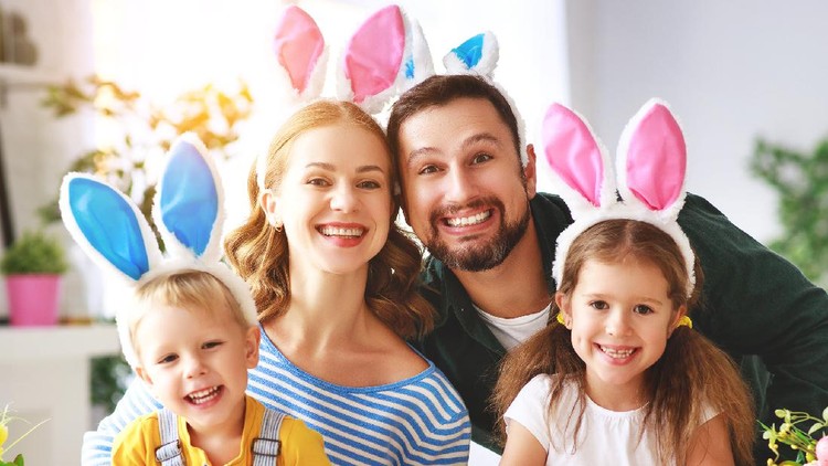 Happy holiday! A mother and her daughter are painting eggs. Family preparing for Easter. Cute little child girl is wearing bunny ears.