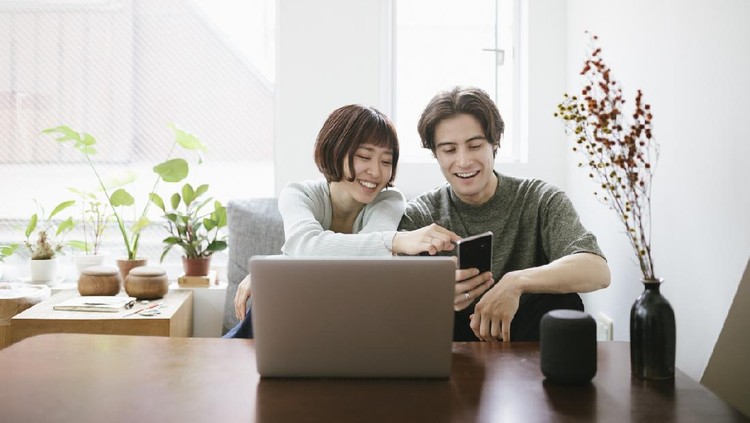 Couple sitting behind a coffee table, installing virtual assistant.
