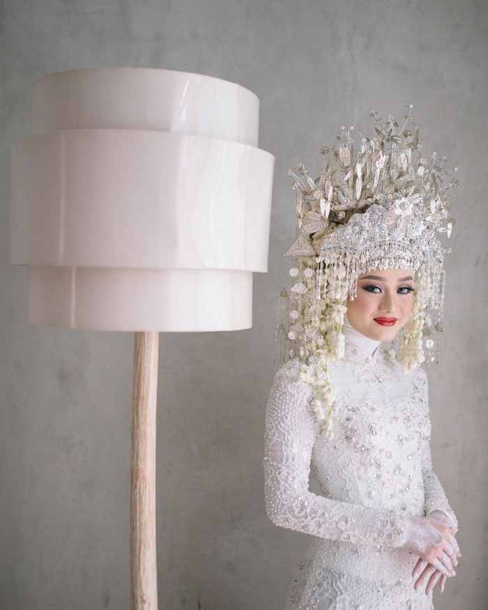 Dinda Hauw tampil cantik dengan kebaya putih berbahan brokat di hari pernikahan. Kebaya putih itu diberi detail beaded warna silver sehingga tampak lebih mewah. Berpadu dengan nuansa adat Palembang, Dinda sangat memesona.(Foto:instagram.com/imagenic)