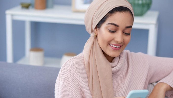 Shot of a young woman using a cellphone while relaxing at home