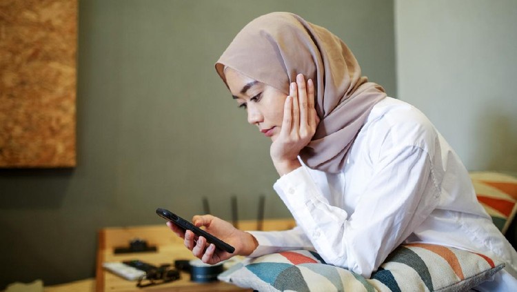 Ilustrasi Ucapan Ramadhan One women looking at the phone during eid celebration in Malaysia