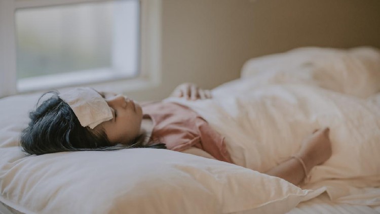an asian chinese sick young girl lying down on bed covered with blanket