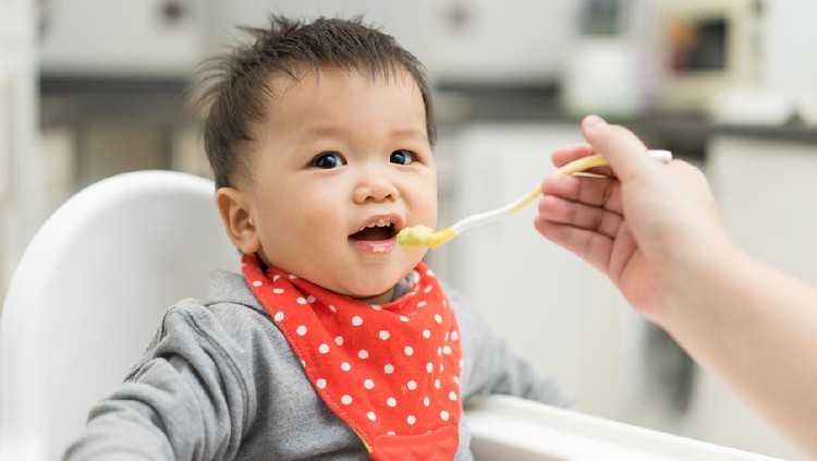 Asian baby boy eating blend food on a high chair