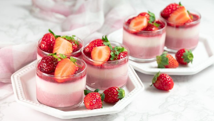Traditional italian dessert vanilla strawberry panna cotta in a glass with fresh berries on a marble background.