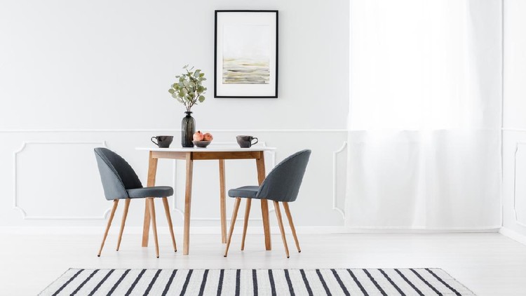 Small dining furniture set and a striped rug in a minimalist white interior with art above the table