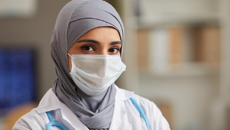 Close-up of muslim female doctor in protective mask looking at camera working at hospital