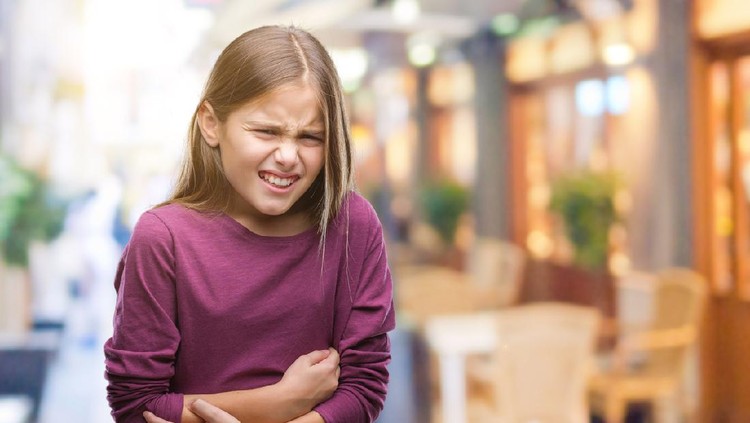 Kid and pills. Abdominal pain in a child. The girl is suffering from pain.