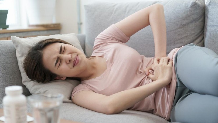 menstruasi asian woman with menstruation and pain period cramps. young women having painful sleeping on sofa at her home