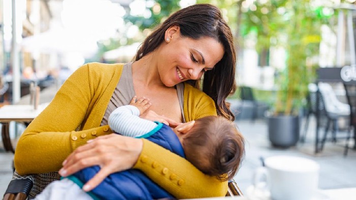 Young mother breastfeeding her baby boy in public while sitting in a cafe