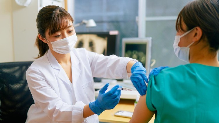 A female medical worker is getting vaccinated in a doctor`s office.