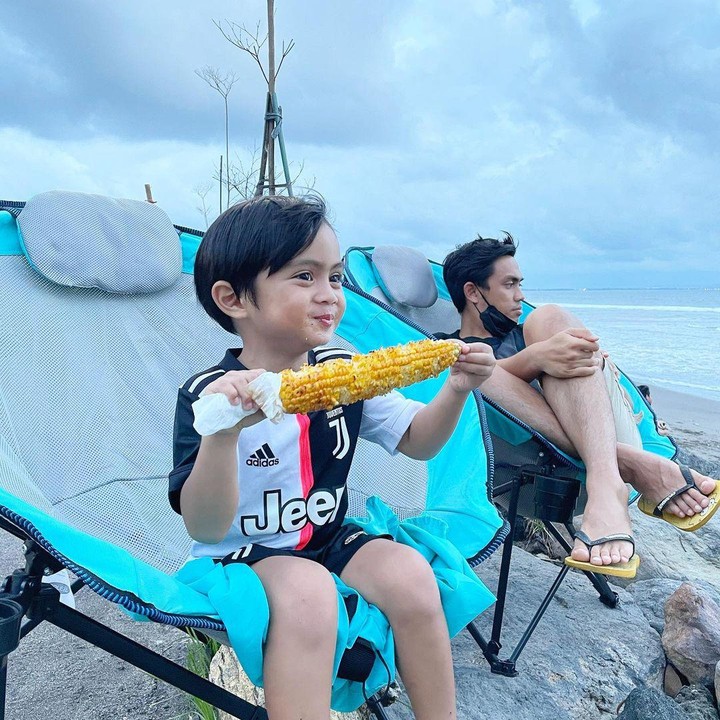 <p>Sekala tampak sangat menikmati suasana Bali. Lihat saja potret keseruannya di pantai. Ia asyik memakan jagung bakar sambil menikmati suasana pantai (Foto: Instagram @dittopercussion).</p>