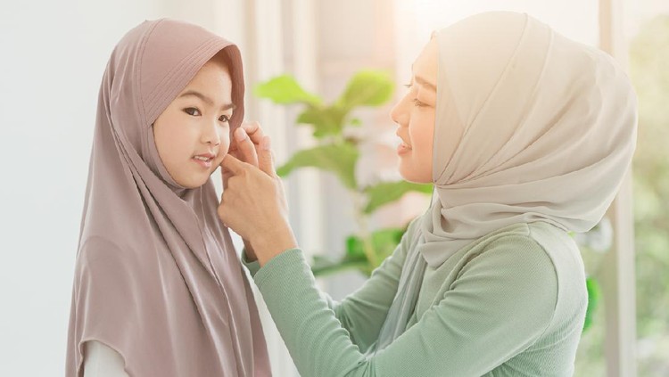 Muslim or Islam mother dressing hijab for her daughter at home in the morning.