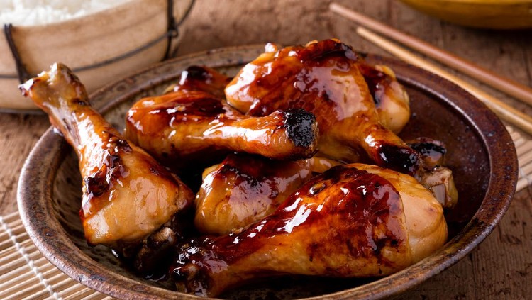A bowl of delicious honey garlic chicken drumsticks with rice.