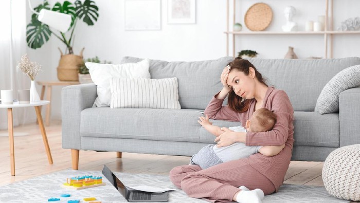 Motherhood Exhaustion Concept. Tired young mom breastfeeding baby and working on laptop at home, feeling frustrated, free space