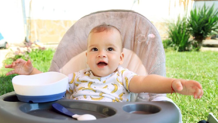 Happy baby boy eating by himself
