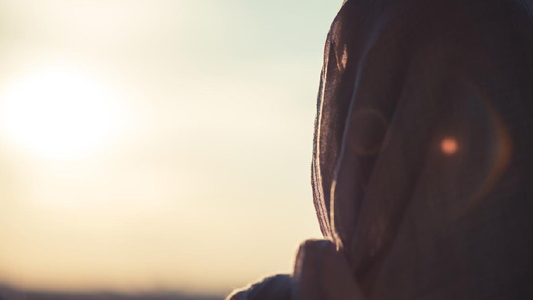 Ilustrasi wanita muslim Arab woman with veil against orange yellow sky