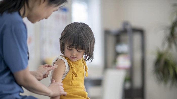 Female nurse gives vaccination to little girl.