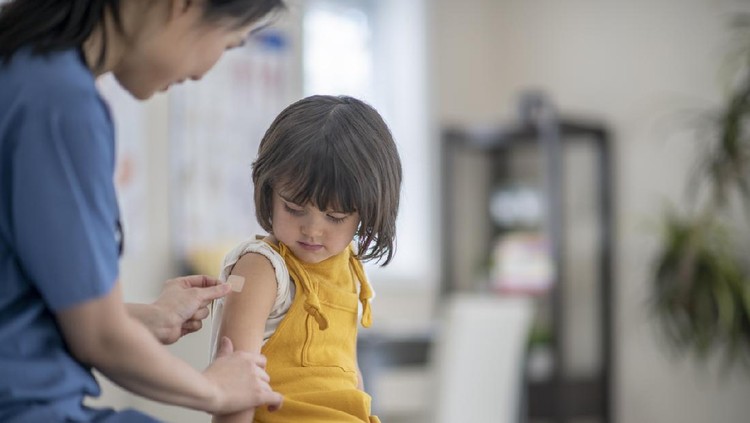 Female nurse gives vaccination to little girl.