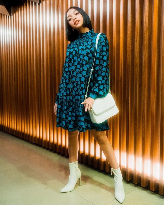 Naura tampil dengan dress klasik becorak dengan long sleeve koleksi Kate Spade New York yang dipadukan dengan boot heels putih yang senada dengan tasnya/Sumber/Instagram/naura.ayu.