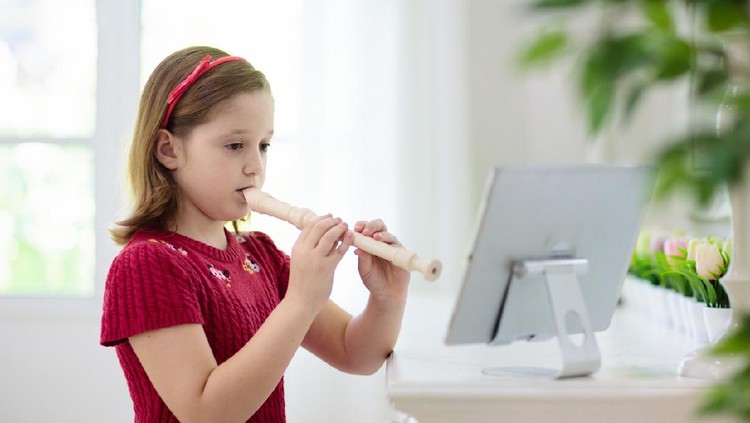 Child playing flute. Remote learning from home. Arts for kid. Little girl with musical instrument. Video chat conference lesson. Online music tuition. Creative children play song. Classical education