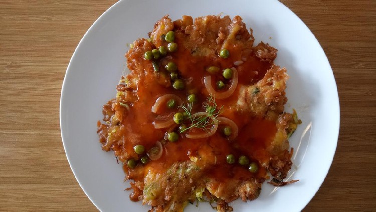 A plate of delicious egg foo young. Egg foo young is an omelette dish with peas and onion and given homemade tomato sauce.
