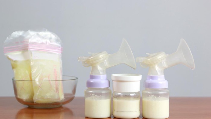 Mother is pouring milk from breast milk storage bags to baby bottle with measuring scale,  Breast Pumping milk concept. selective focus.