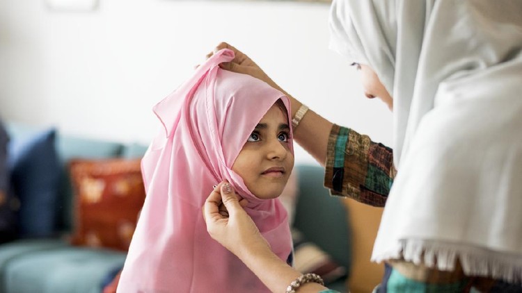 Muslim mom teaching daughter how to wear a Hijab