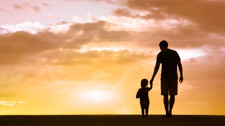 Loving father walking side by side with son holding hands.