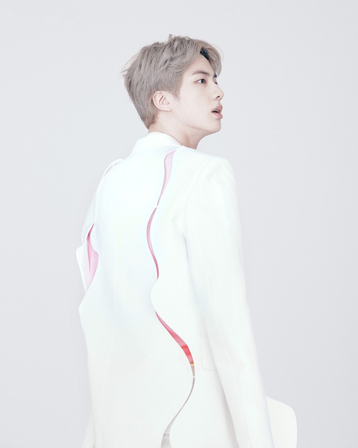 Jin memadukan setelan jas putih dengan kaos berwarna pink. Uniknya, jas yang ia kenakan memiliki detai cut-out di bagian belakang. (foto: instagram.com/louisvuitton)