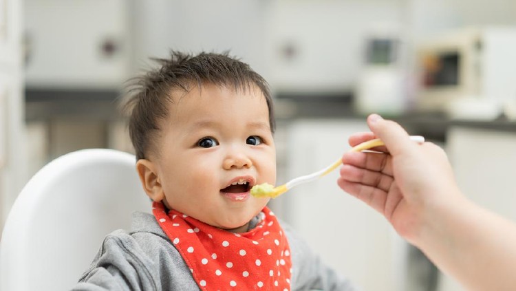 Asian baby boy eating blend food on a high chair