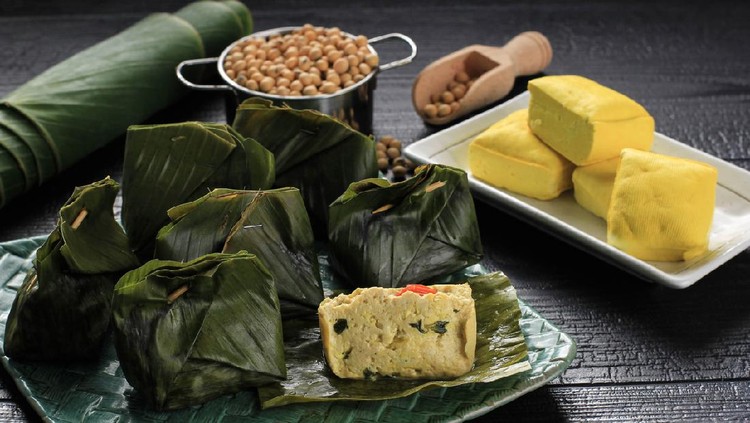 Pepes Tahu is Indonesian Spiced Tofu Wrapped with Banana Leaf and Steamed, Typically Indonesian Food from West Java (Sundanese). Steamed Tofu with Asian Basil. Served on Woven Plate, Black Background