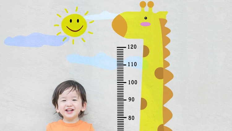 Closeup happy asian kid stand for measure height with cute cartoon at the marble stone wall textured background