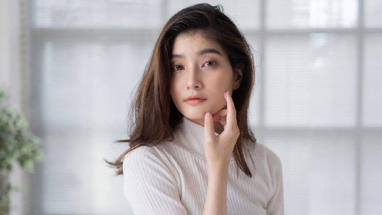 Asian woman is applying cream to her face.