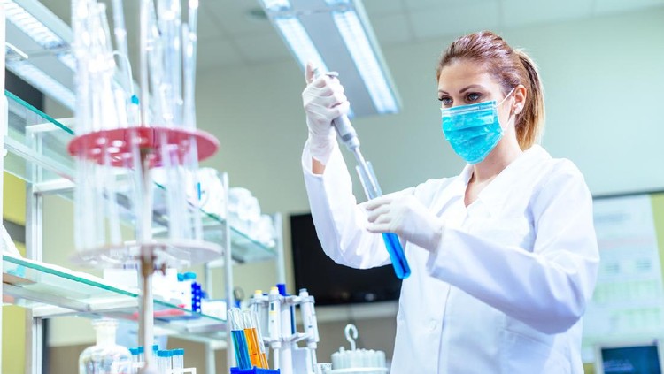 Woman in laboratory, examining new potions for the scientific research at university. Woman is wearing protective mask and protective gloves (Surgical gloves) while working with beakers, test tubes and other lab equipment. Series of images, taken with Nikon D800 and 50mm or 85 mm professional lens, developed from RAW.