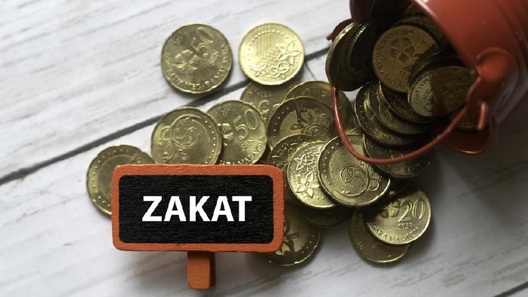 zakat Selective focus of red bucket full with gold coins and red tag written with ZAKAT on white wooden background.