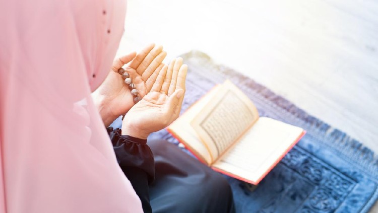 side of asian young beautiful muslim woman pray with beads and read quran sit on carpet mat with meditation in mosque.