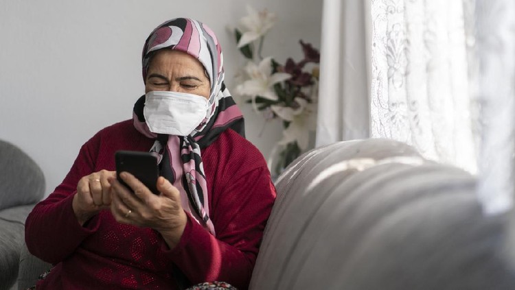 Senior muslim woman using mobile phone at home during Covid-19 pandemic