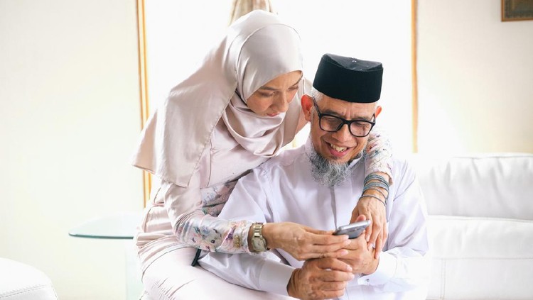 Father and daughter looking at phone during raya celebration in Malaysia