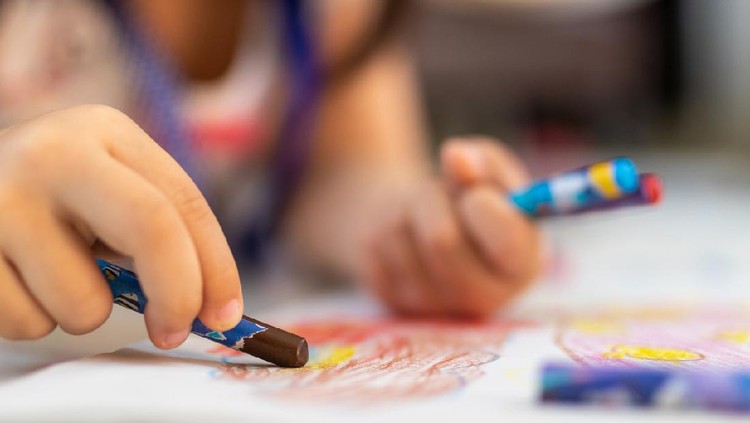 Close up of little hands coloring with Crayon