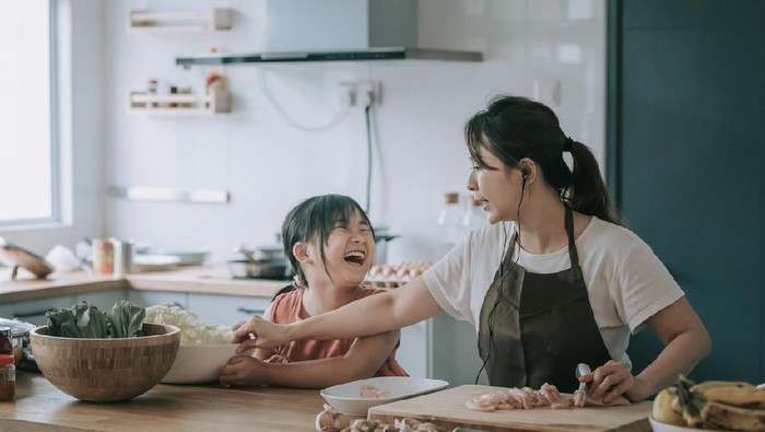 an asian chinese mother cooking preparing food at kitchen counter  with her daughter