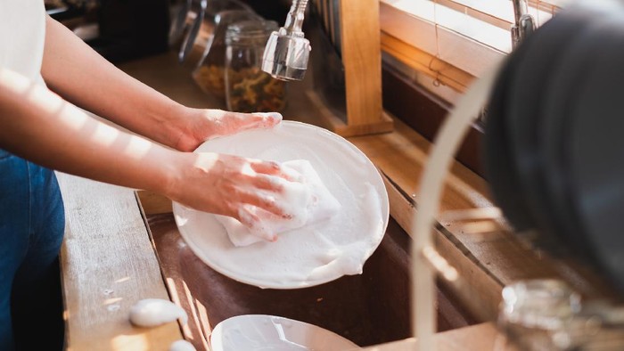 Close up maid housewife washing cleaning dishes in kitchen