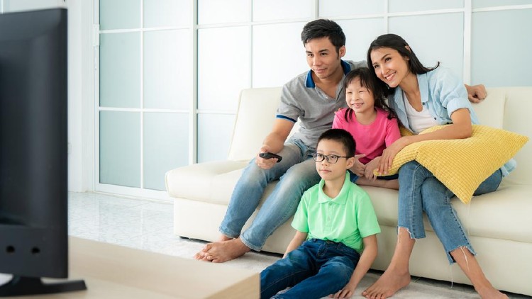 Asian happy family with father, mother, son and daughter sitting in sofa and watching television at home concept of family values, vacation day, holiday, happiness or lifestyle.