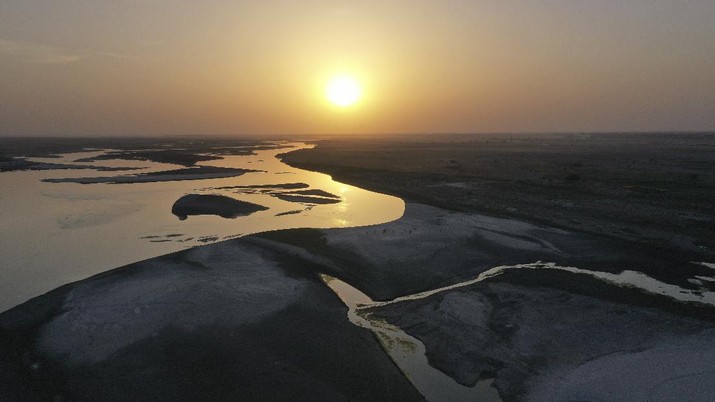 Sun sets over the river of basin of the Ganges , one of India's holiest rivers with falling levels of water in its lower reaches on the world Earth Day in Prayagraj, India, Thursday, April 22, 2021. (AP Photo/Rajesh Kumar Singh)