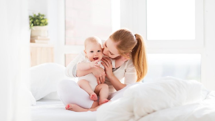 happy family mother playing and hug with newborn baby  in bed