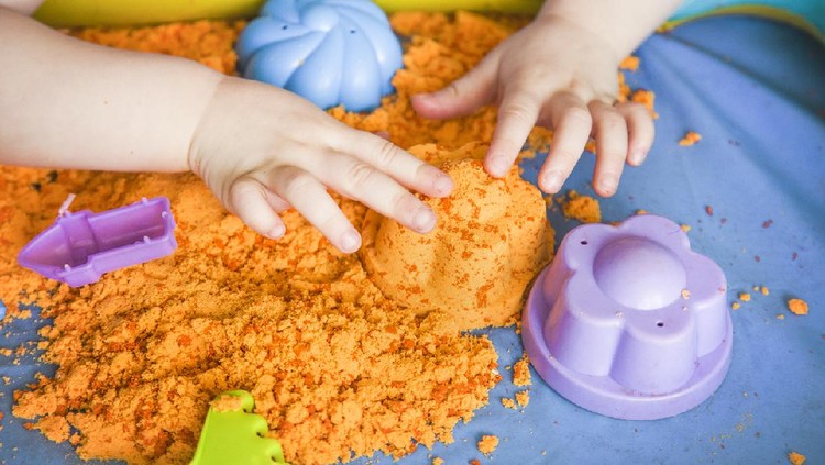 The hands of a child girl playing with kinetic sand. development of fine motor skills.