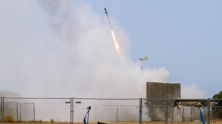 A Israeli soldier takes cover as an Iron Dome air defense system launches to intercept a rocket from the Gaza Strip, in Ashkelon, southern Israel, Tuesday, May 11, 2021. (AP Photo/Ariel Schalit)