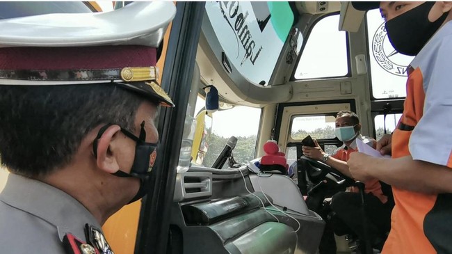 Polisi memeriksa seluruh penumpang bus karena tidak membawa surat sehat Covid.