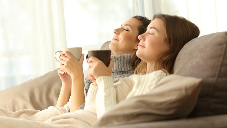 Two relaxed roommates in winter sitting on a sofa in the living room of a house interior